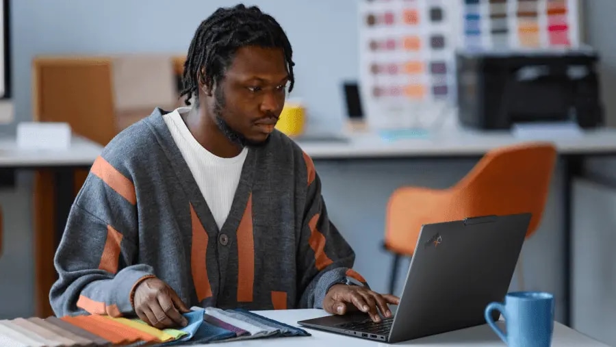 一位男子坐在桌前,正在使用 Lenovo ThinkPad X1 筆記型電腦看色彩樣板。