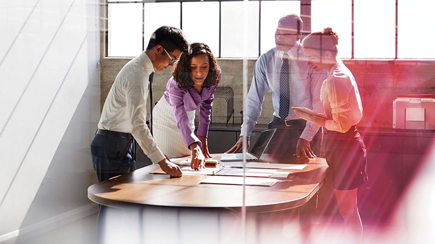 五人圍坐在會議室桌旁,看著 Lenovo 筆記型電腦。